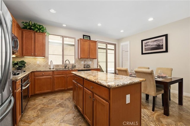 kitchen with a sink, decorative backsplash, a kitchen island, light stone counters, and recessed lighting
