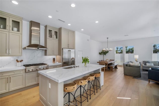 2047 Doheny Way, Dana Point, CA 92629 - kitchen featuring wall chimney range hood, stainless steel appliances, a sink, cream cabinets, and a center island with sink