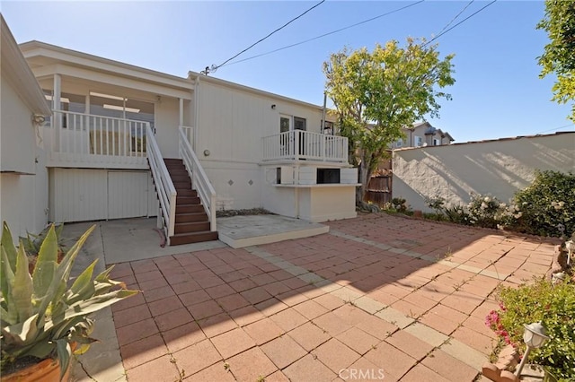 rear view of property featuring stairway, a patio, and fence