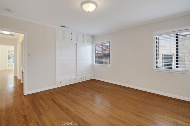 spare room featuring light wood finished floors, baseboards, ornamental molding, and a smoke detector