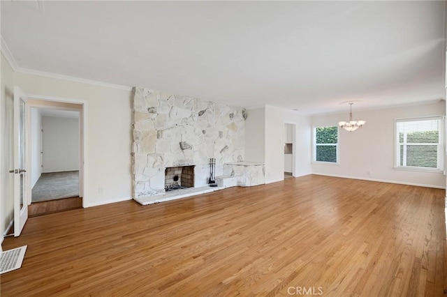 unfurnished living room with a chandelier, light wood-style floors, a fireplace, crown molding, and baseboards