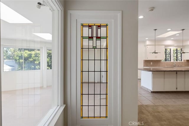doorway to outside featuring plenty of natural light, recessed lighting, light tile patterned floors, and a sink