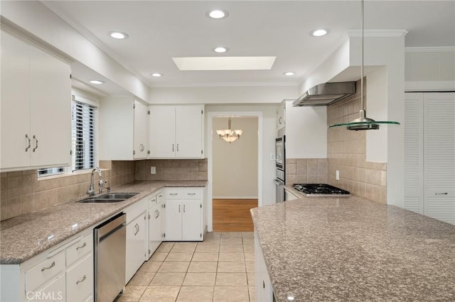 kitchen featuring a sink, stainless steel appliances, a skylight, backsplash, and light tile patterned floors