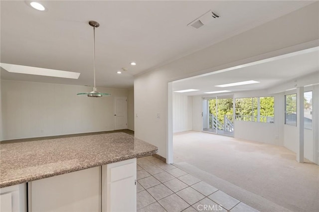 kitchen with open floor plan, recessed lighting, white cabinetry, light tile patterned flooring, and light colored carpet