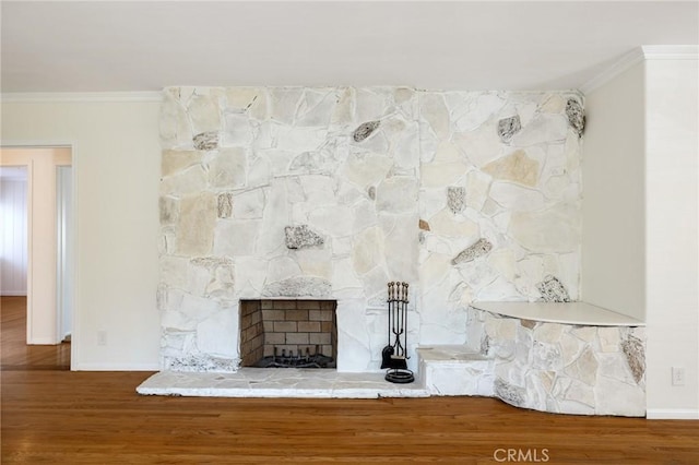 detailed view of ornamental molding, wood finished floors, baseboards, and a fireplace