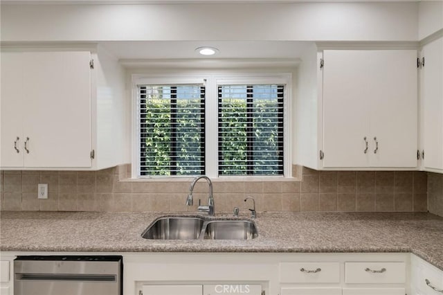 kitchen with a sink, white cabinets, stainless steel dishwasher, and decorative backsplash