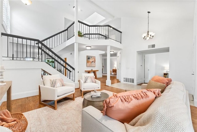 15 Firestone Unit 4, Irvine, CA 92614 - living room featuring high vaulted ceiling, stairs, light wood-style flooring, a chandelier, and baseboards