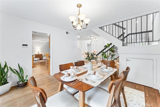 15 Firestone Unit 4, Irvine, CA 92614 - dining room featuring a chandelier, stairs, light wood-style flooring, and baseboards