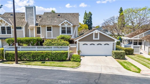 15 Firestone Unit 4, Irvine, CA 92614 - tudor house with a chimney, concrete driveway, fence, stucco siding, and a garage