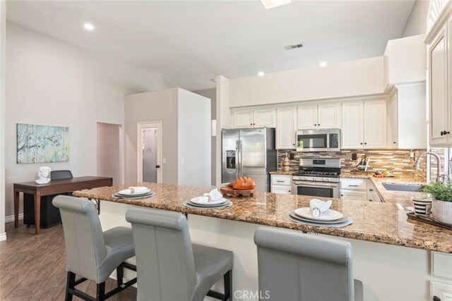 1044 Shadow Crest Cir, Corona, CA 92881 - kitchen with stainless steel appliances, a sink, light stone countertops, light wood finished floors, and decorative backsplash