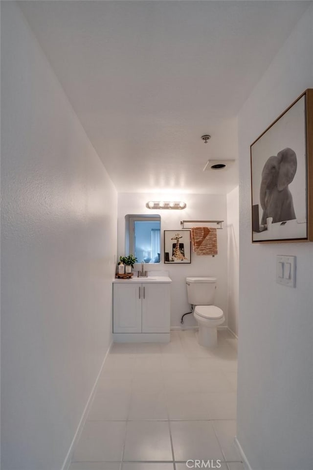 bathroom with toilet, tile patterned floors, vanity, and baseboards
