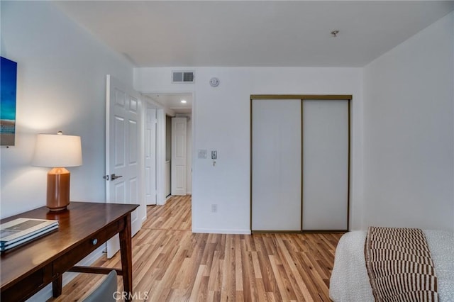 bedroom featuring light wood-style floors, a closet, and an office area