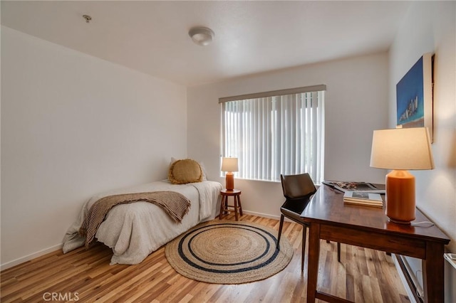 bedroom featuring wood finished floors, baseboards, and a desk