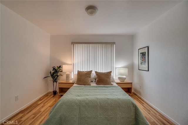 bedroom featuring light wood finished floors and baseboards