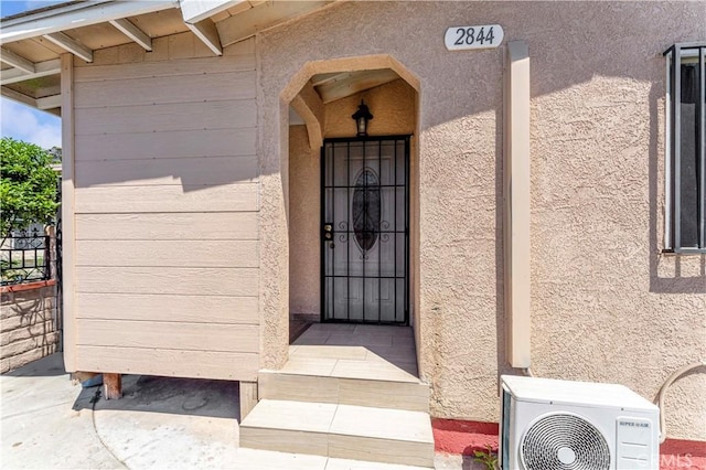 property entrance with stucco siding and a cooling unit