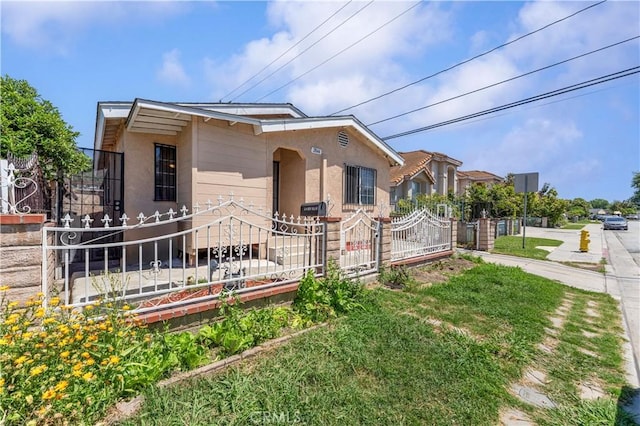 view of front of property with fence, stucco siding, and a gate