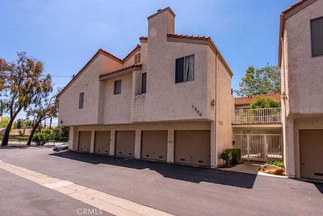 3306 Darby St Unit 402, Simi Valley, CA 93063 - view of side of home with a tiled roof, a chimney, stucco siding, and an attached garage