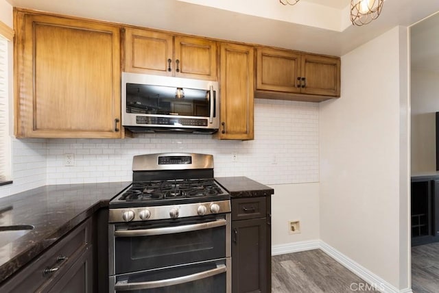 3306 Darby St Unit 402, Simi Valley, CA 93063 - kitchen with stainless steel appliances, dark wood-style floors, baseboards, dark stone countertops, and decorative backsplash