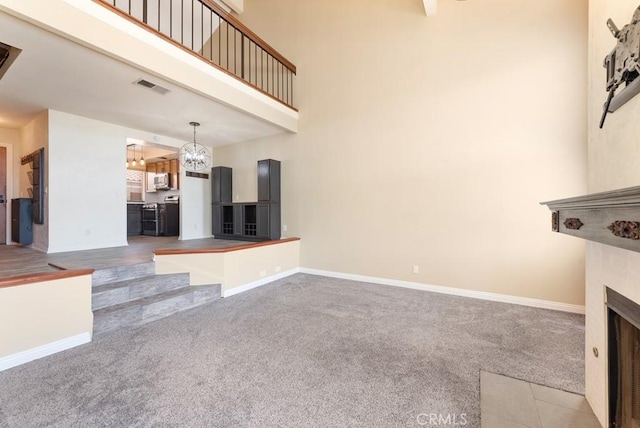 3306 Darby St Unit 402, Simi Valley, CA 93063 - unfurnished living room with carpet floors, a fireplace, a chandelier, baseboards, and a towering ceiling