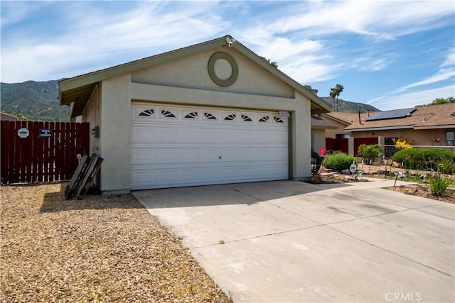 18993 Janisse Ln, Lake Elsinore, CA 92530 - view of front of home featuring stucco siding, concrete driveway, a mountain view, and fence