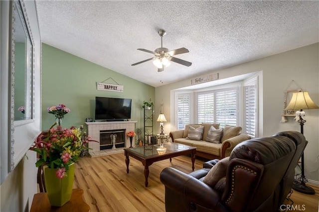 18993 Janisse Ln, Lake Elsinore, CA 92530 - living area with lofted ceiling, a ceiling fan, wood finished floors, a textured ceiling, and a tile fireplace