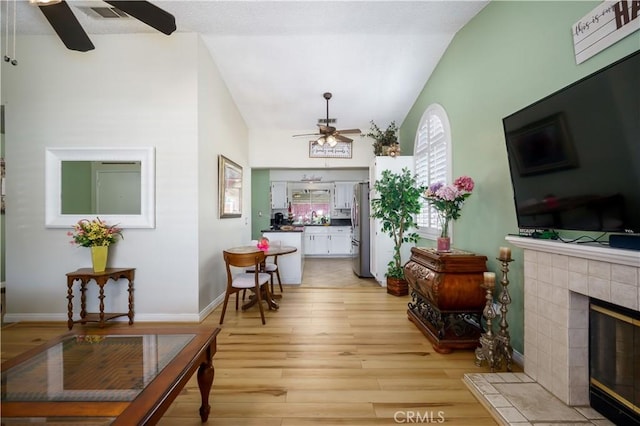 18993 Janisse Ln, Lake Elsinore, CA 92530 - living room with a ceiling fan, lofted ceiling, a tile fireplace, light wood-style floors, and baseboards