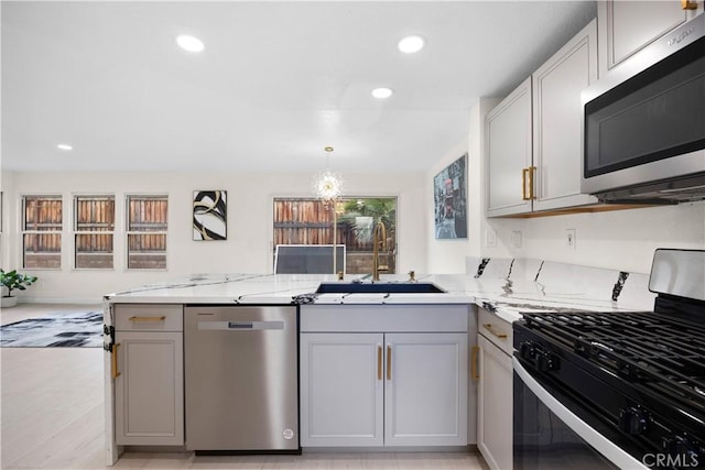 2407 Galisteo St, Corona, CA 92882 - kitchen featuring appliances with stainless steel finishes, a sink, gray cabinetry, a peninsula, and light stone counters