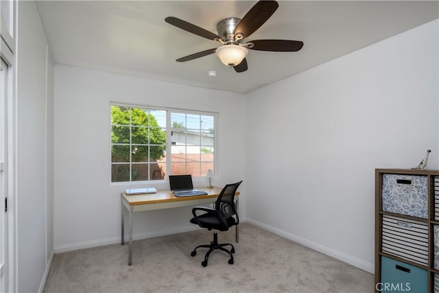 carpeted home office with ceiling fan and baseboards