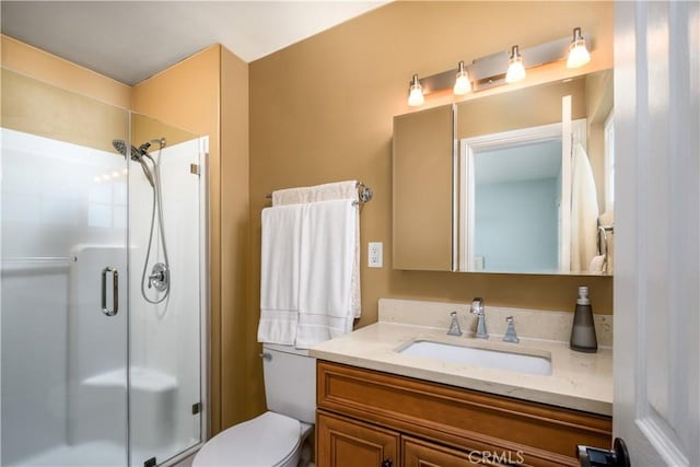 bathroom with a shower stall, toilet, and vanity