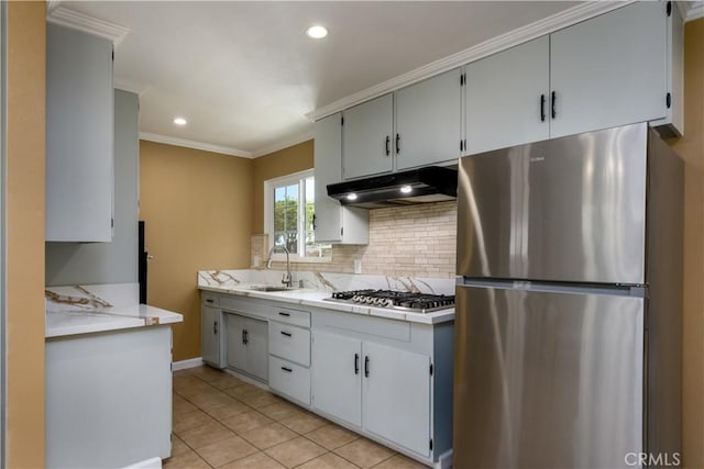 kitchen featuring appliances with stainless steel finishes, under cabinet range hood, a sink, decorative backsplash, and light tile patterned floors
