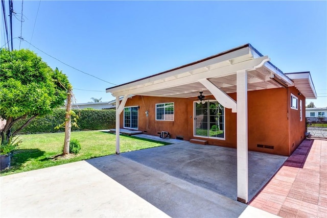 rear view of house with ceiling fan, a patio, stucco siding, and crawl space