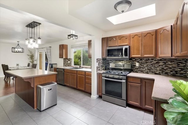 13607 Chaparral Trl, Yucaipa, CA 92399 - kitchen featuring appliances with stainless steel finishes, a sink, decorative backsplash, pendant lighting, and brown cabinets