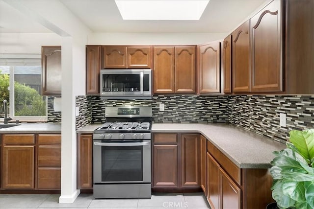13607 Chaparral Trl, Yucaipa, CA 92399 - kitchen with appliances with stainless steel finishes, a sink, a skylight, light tile patterned flooring, and backsplash