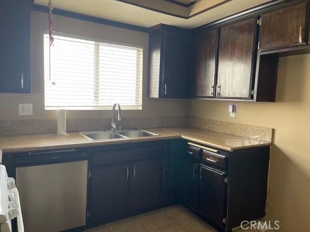 kitchen with dishwashing machine, a sink, light countertops, blue cabinets, and light tile patterned floors