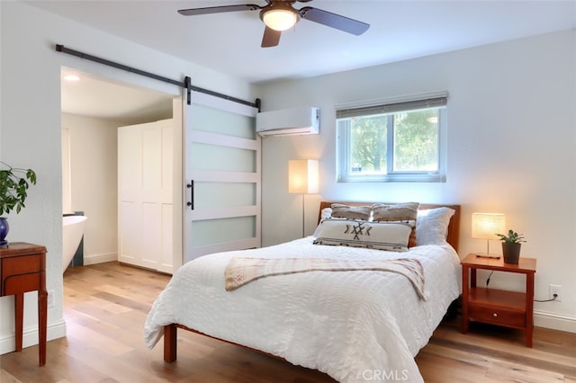 5192 Oak Rd, Mariposa, CA 95345 - bedroom with wood finished floors, a barn door, an AC wall unit, a ceiling fan, and baseboards