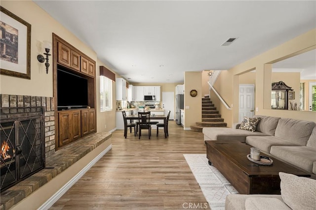 23725 Scarlet Oak Dr, Murrieta, CA 92562 - living room featuring a brick fireplace, light wood finished floors, stairway, and plenty of natural light