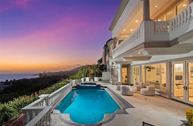 71 Ritz Cove Dr, Dana Point, CA 92629 - pool at dusk featuring a patio, a pool with connected hot tub, french doors, and stairway