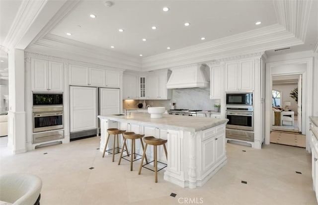 71 Ritz Cove Dr, Dana Point, CA 92629 - kitchen with custom exhaust hood, black microwave, a large island with sink, a breakfast bar, and white cabinetry