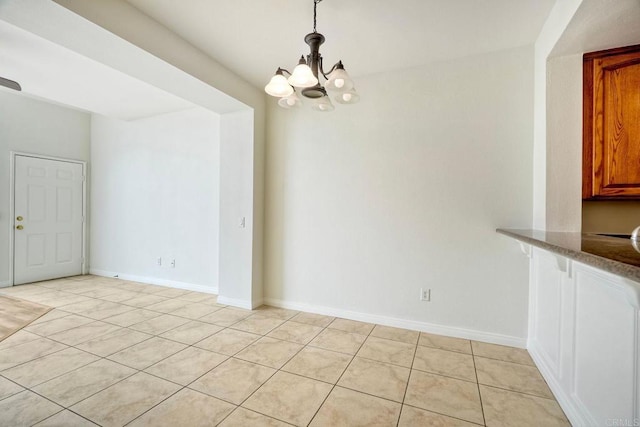 unfurnished dining area featuring light tile patterned floors, a chandelier, and baseboards
