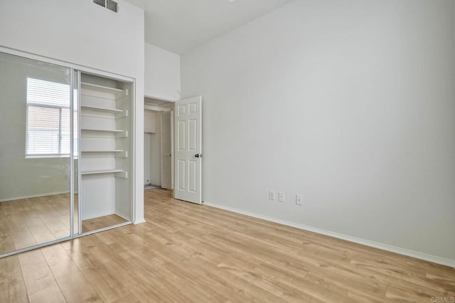 unfurnished bedroom featuring light wood-style flooring, baseboards, and a closet