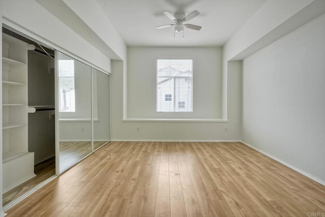 unfurnished bedroom with multiple windows, wood finished floors, baseboards, and a closet