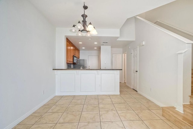 kitchen with dark countertops, a chandelier, black microwave, pendant lighting, and light tile patterned flooring