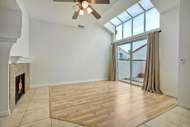 unfurnished living room featuring ceiling fan, light wood-style flooring, high vaulted ceiling, and baseboards