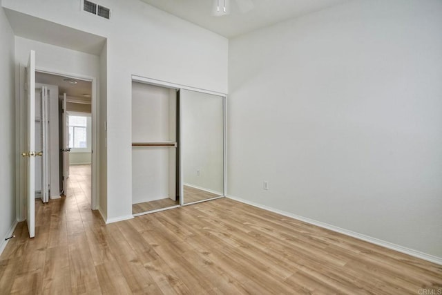 unfurnished bedroom featuring light wood-type flooring, baseboards, and a closet