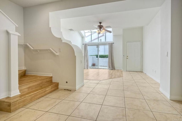 entrance foyer with ceiling fan, stairway, light tile patterned flooring, and baseboards
