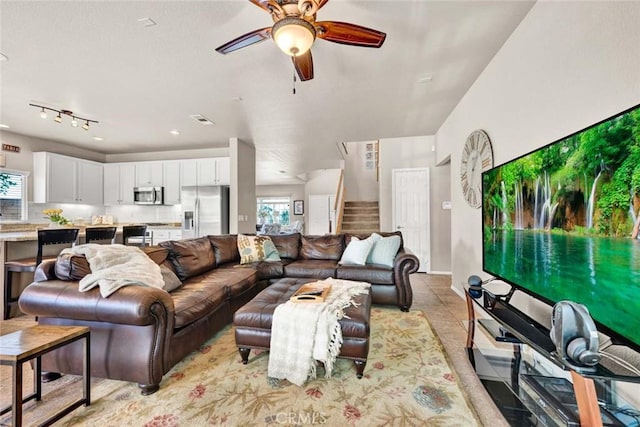 living area featuring ceiling fan, stairs, and baseboards