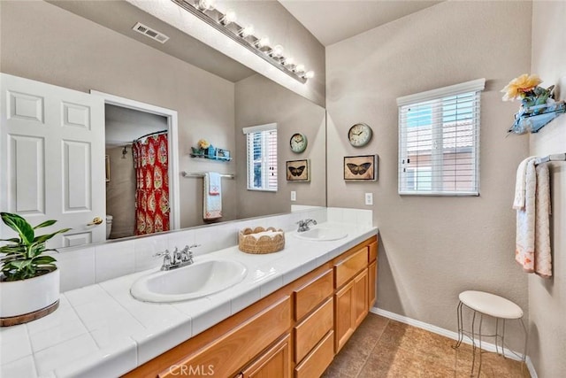 bathroom with plenty of natural light, baseboards, double vanity, and tile patterned floors