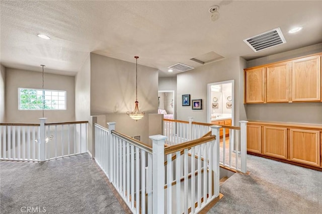 hallway with an upstairs landing, carpet floors, a textured ceiling, and recessed lighting
