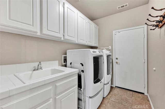 washroom featuring washing machine and clothes dryer, cabinet space, baseboards, and light tile patterned flooring