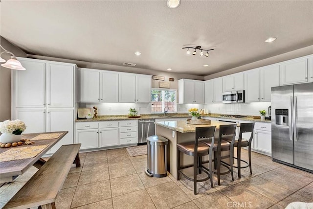 kitchen featuring stainless steel appliances, a kitchen island, white cabinets, a sink, and recessed lighting